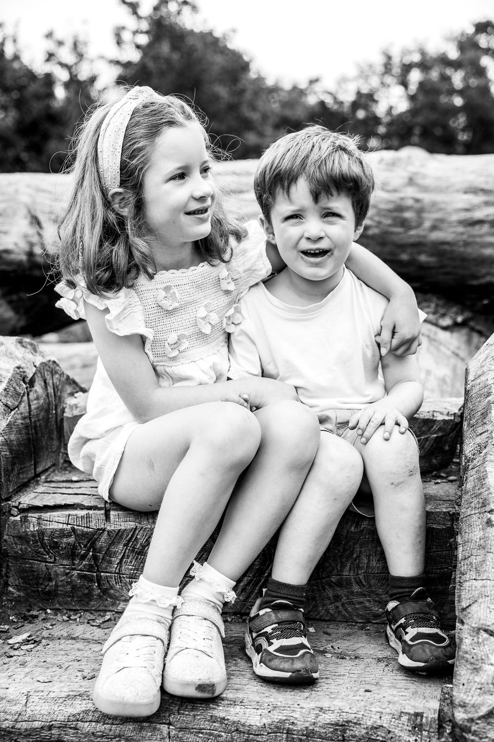 young siblings sitting on wooden bench