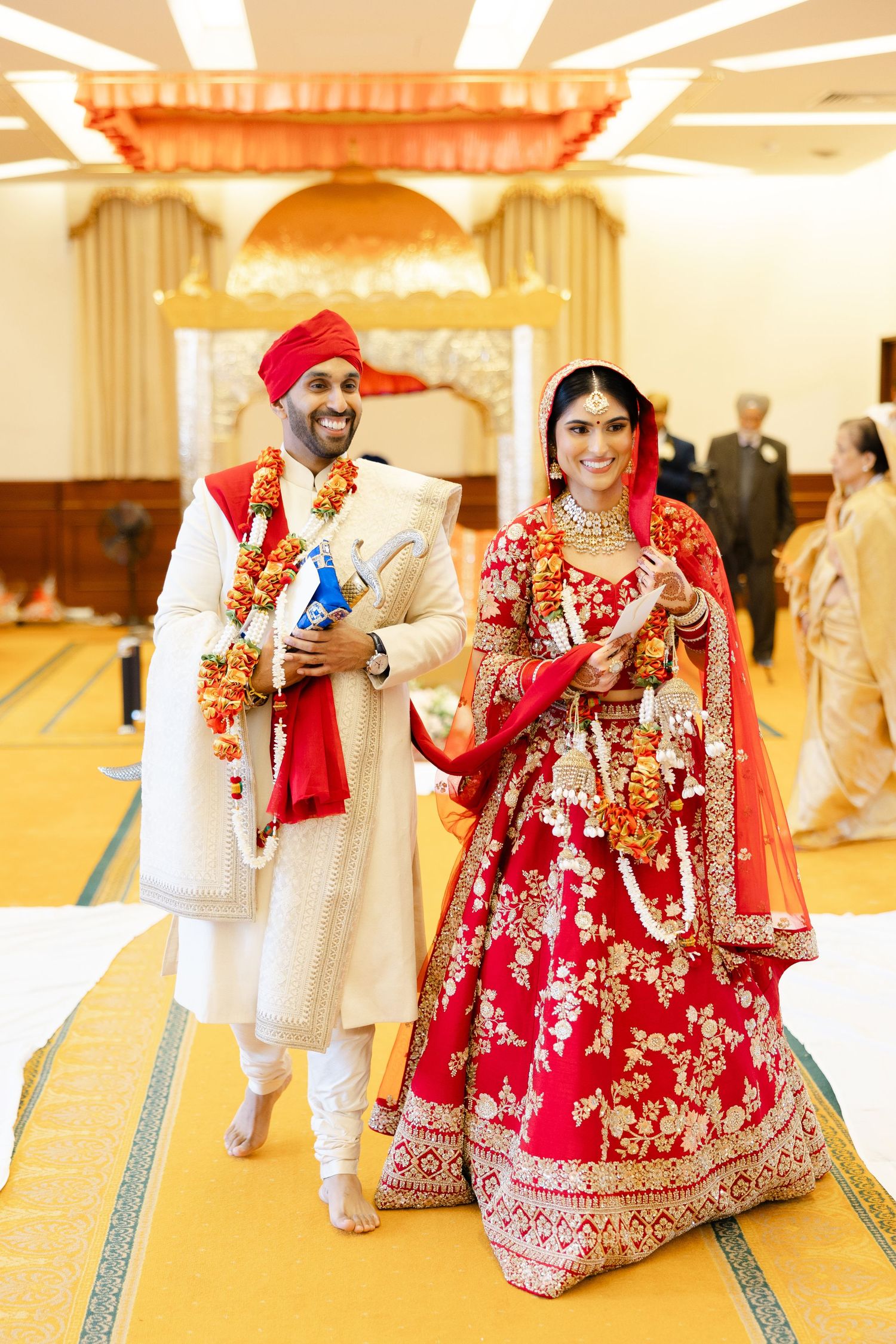 Happy Sikh bride and groom walking in Hounslow Gurdwara