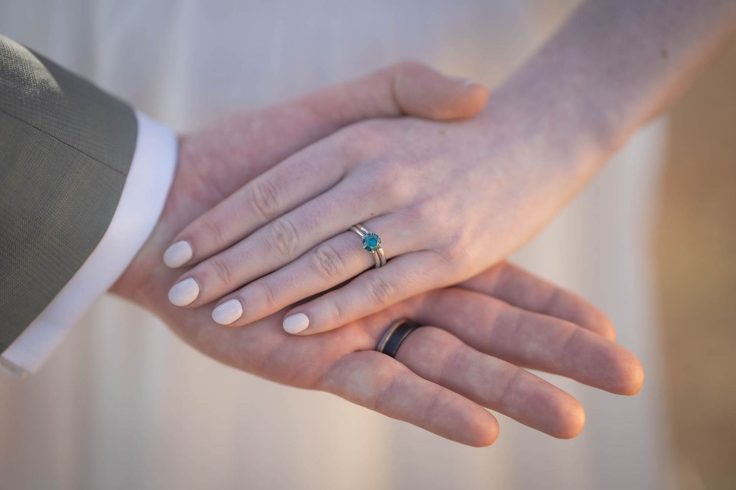 Close-up of hands showing wedding rings against a white background.