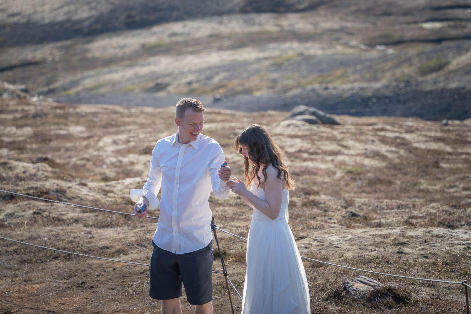 Couple laughing together on a rugged mountain landscape during their outdoor adventure session.