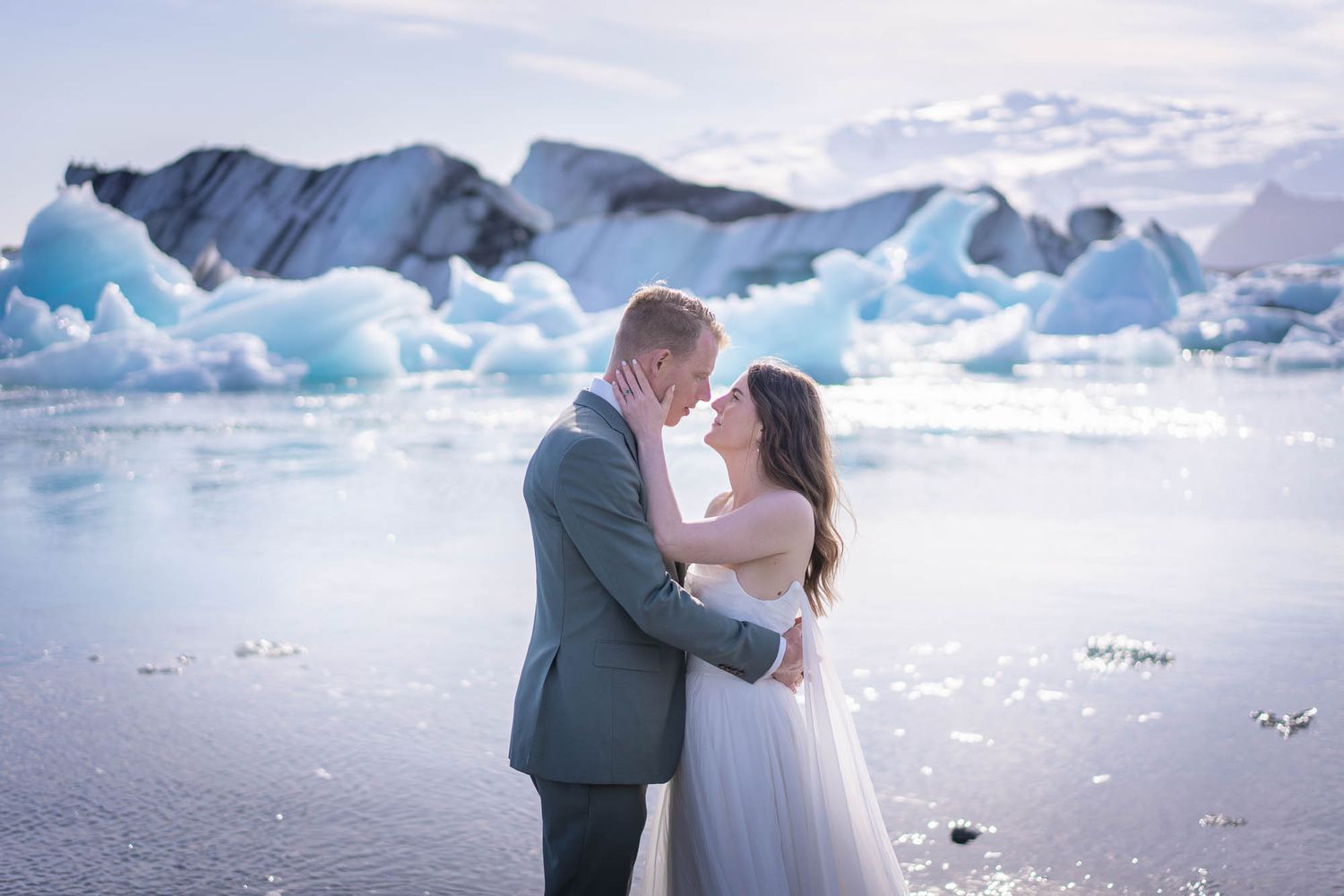 A romantic wedding shoot by an icy glacier lake with blue ice formations and snowy mountains.