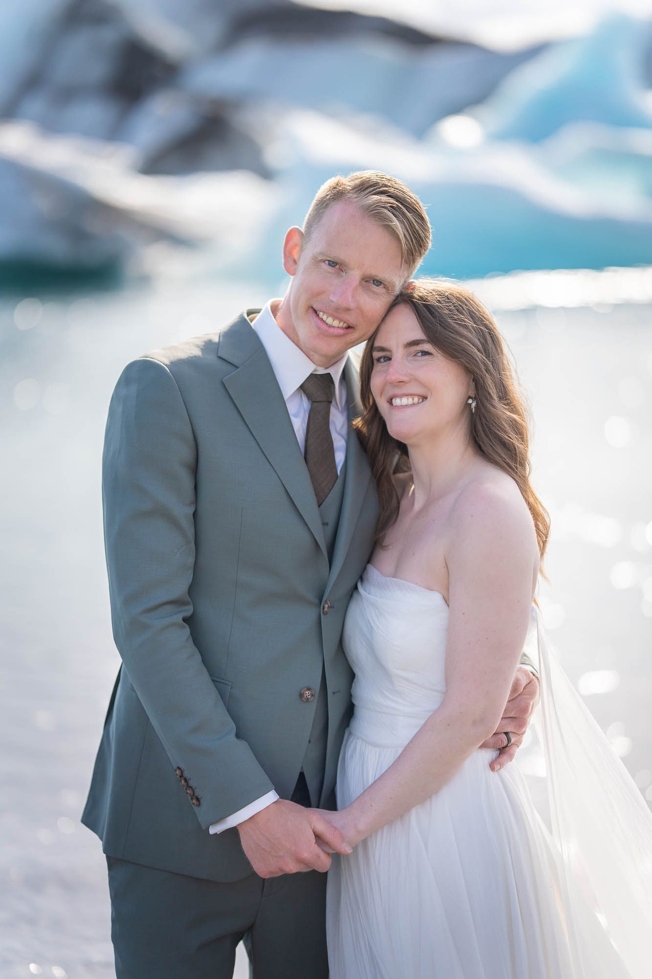 A wedding couple sharing intimate moments in front of a glacial landscape with bright sunlight.