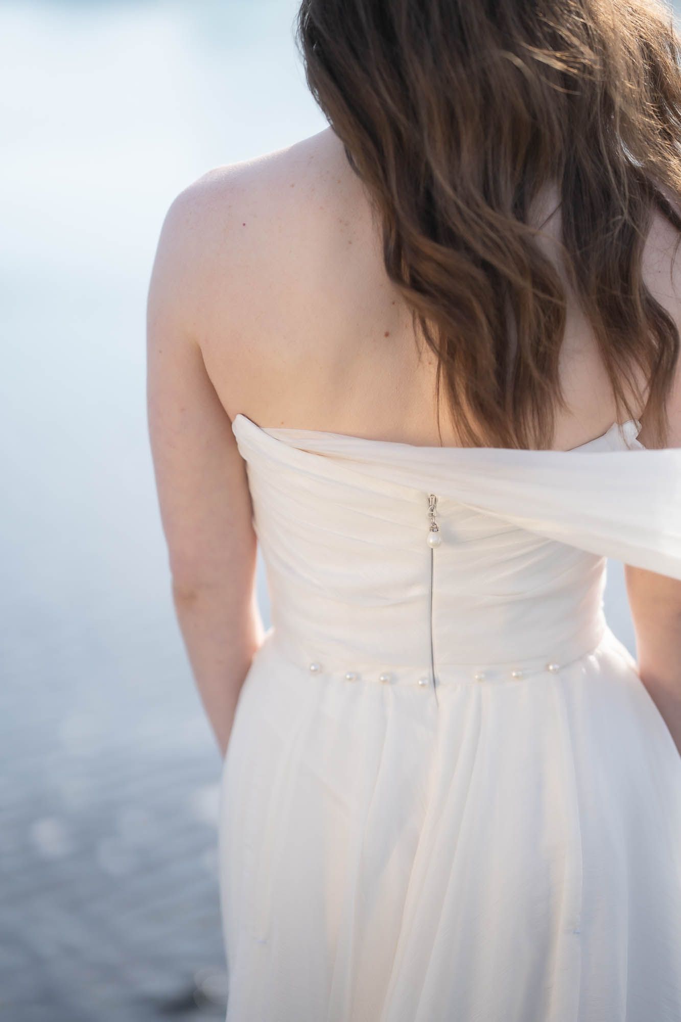 Close-up details of an elegant white wedding dress back with zipper closure.