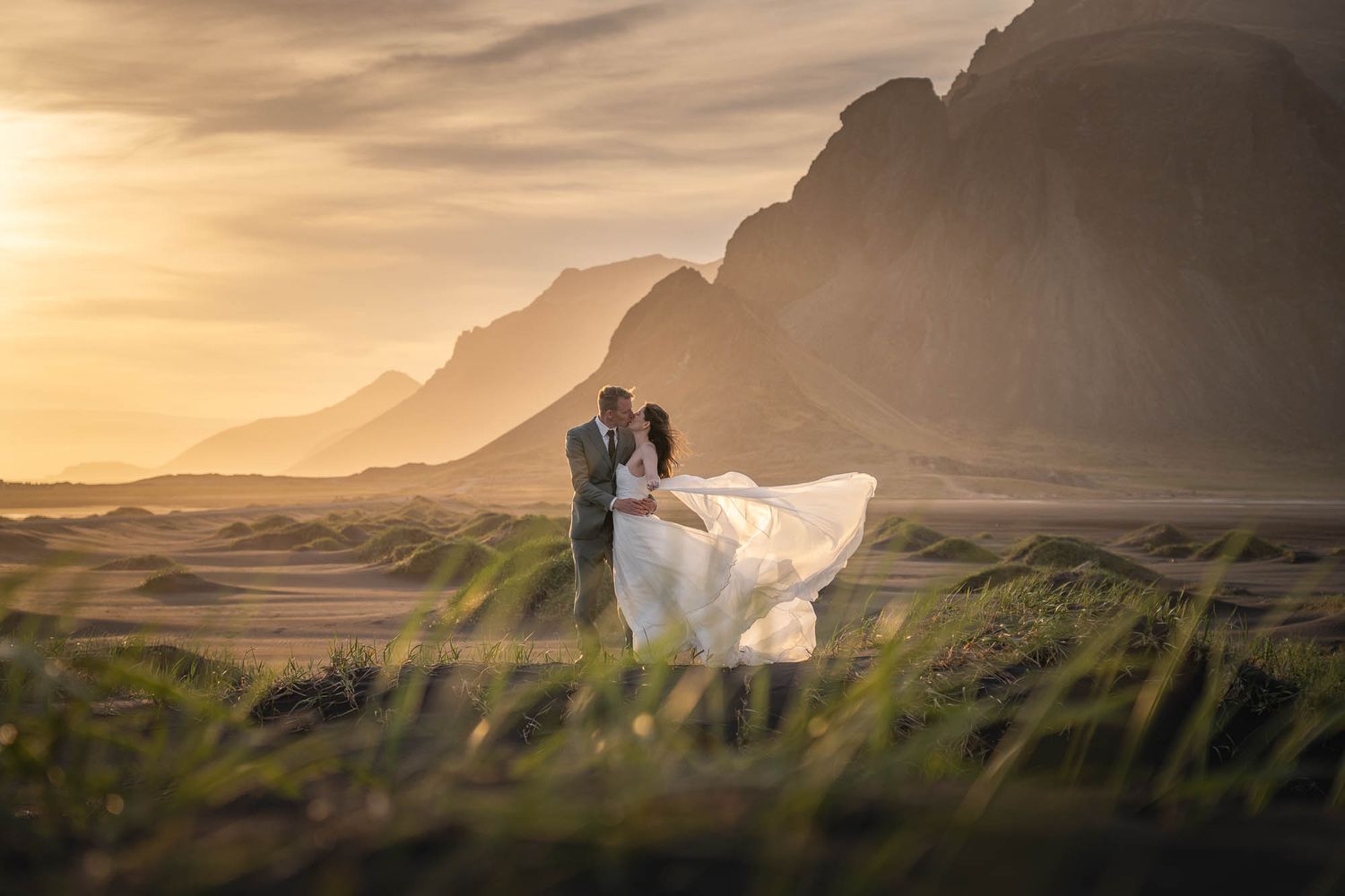 Silhouetted figures against a golden sunset in a dramatic mountain landscape.