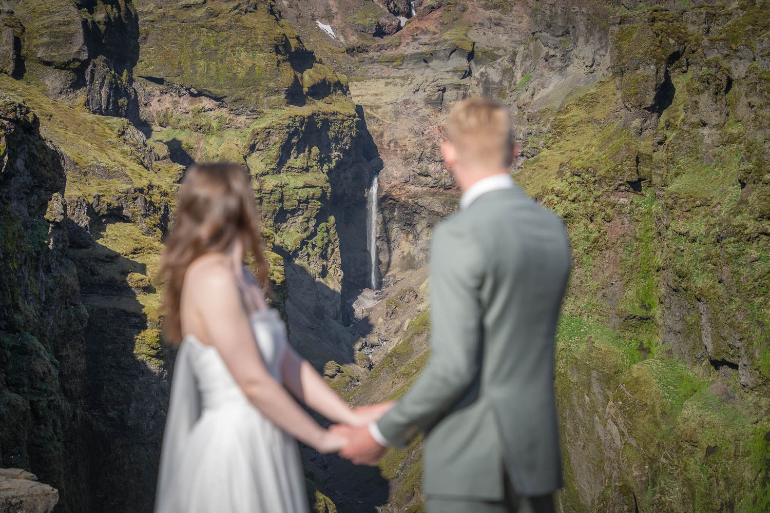 Couple exchanging vows on a scenic mountain overlook with dramatic cliffs and waterfalls.