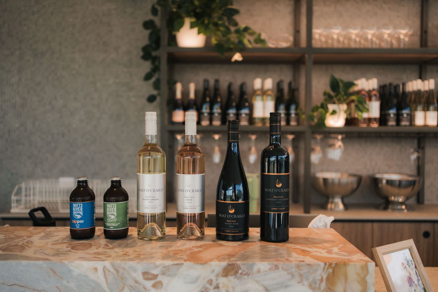 Various bottles of wine and beverages displayed on a rustic wooden bar counter.