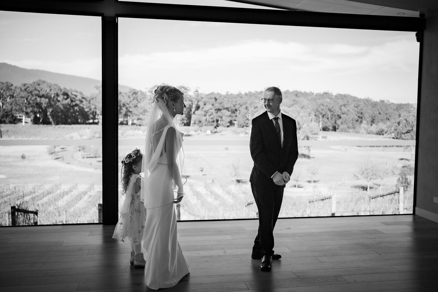 A candid wedding moment captured in black and white on a covered deck with mountain views.
