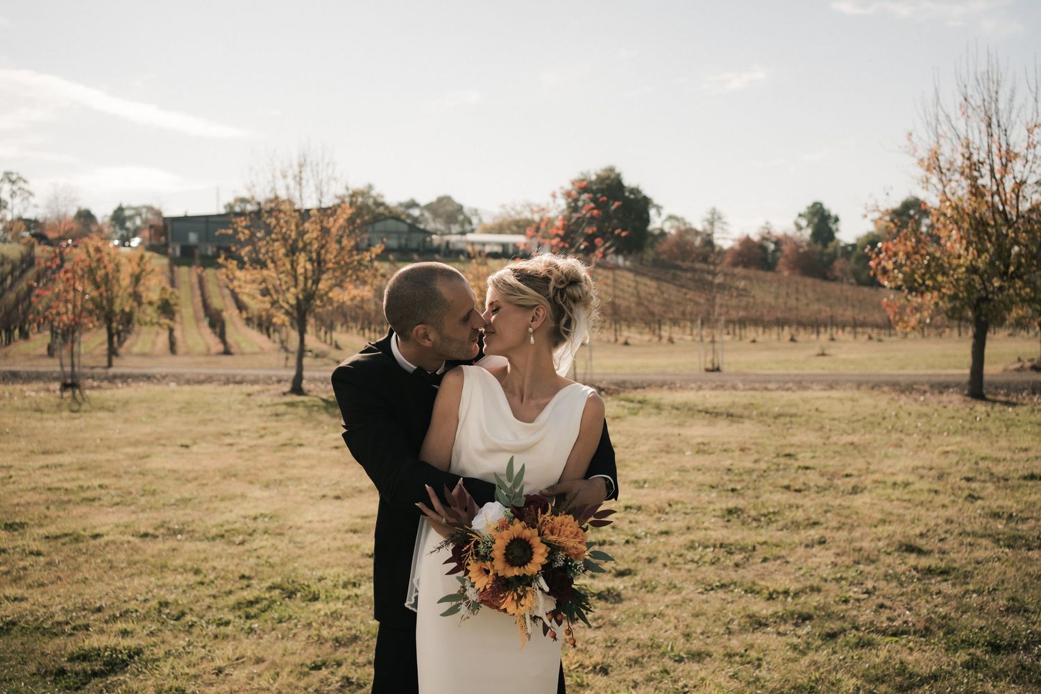 Natural fall boho wedding photography of sunflower bouquets and pastel flowers in rustic outdoor autumn setting.