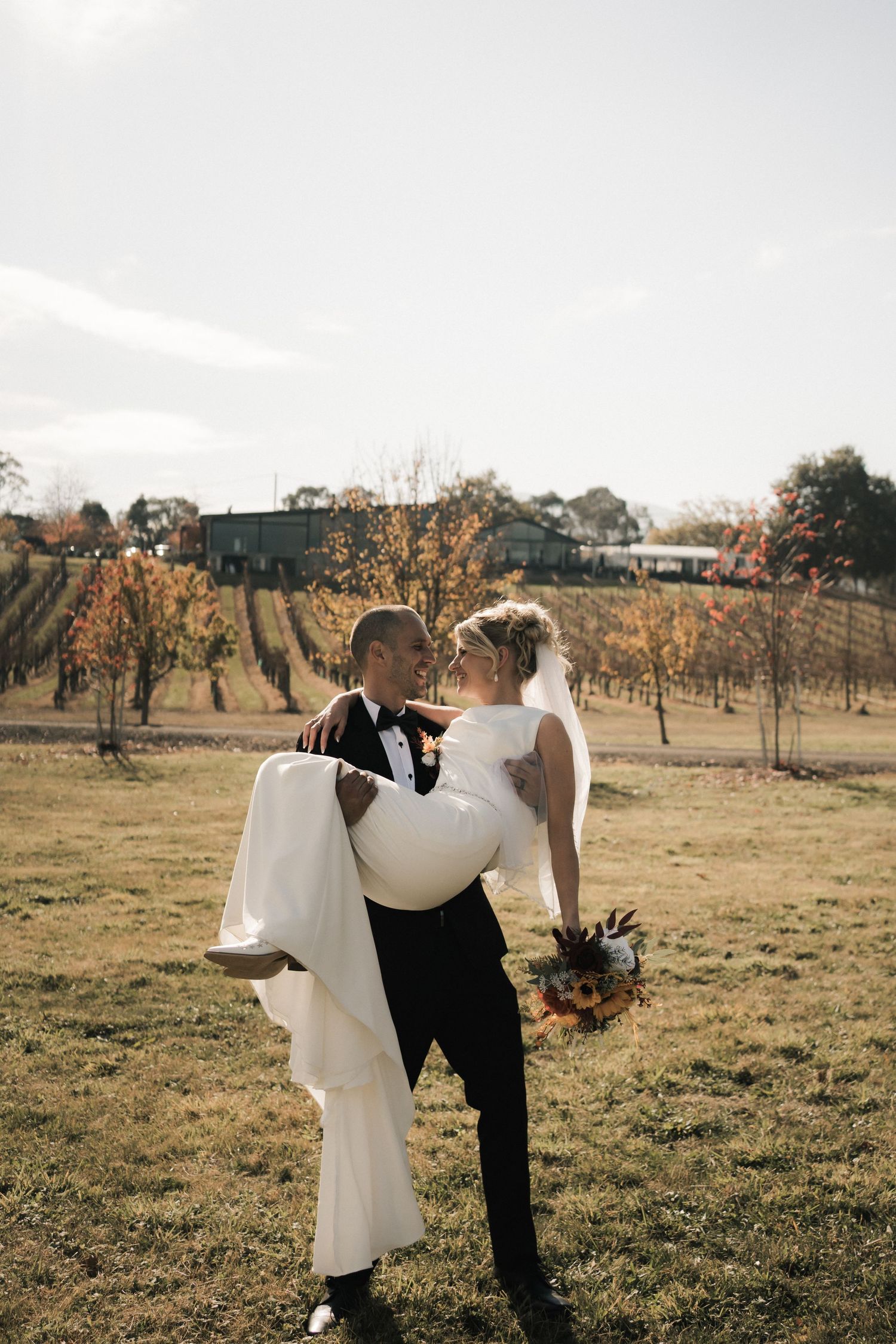 Couple walking through vineyard at sunset during wedding photoshoot.