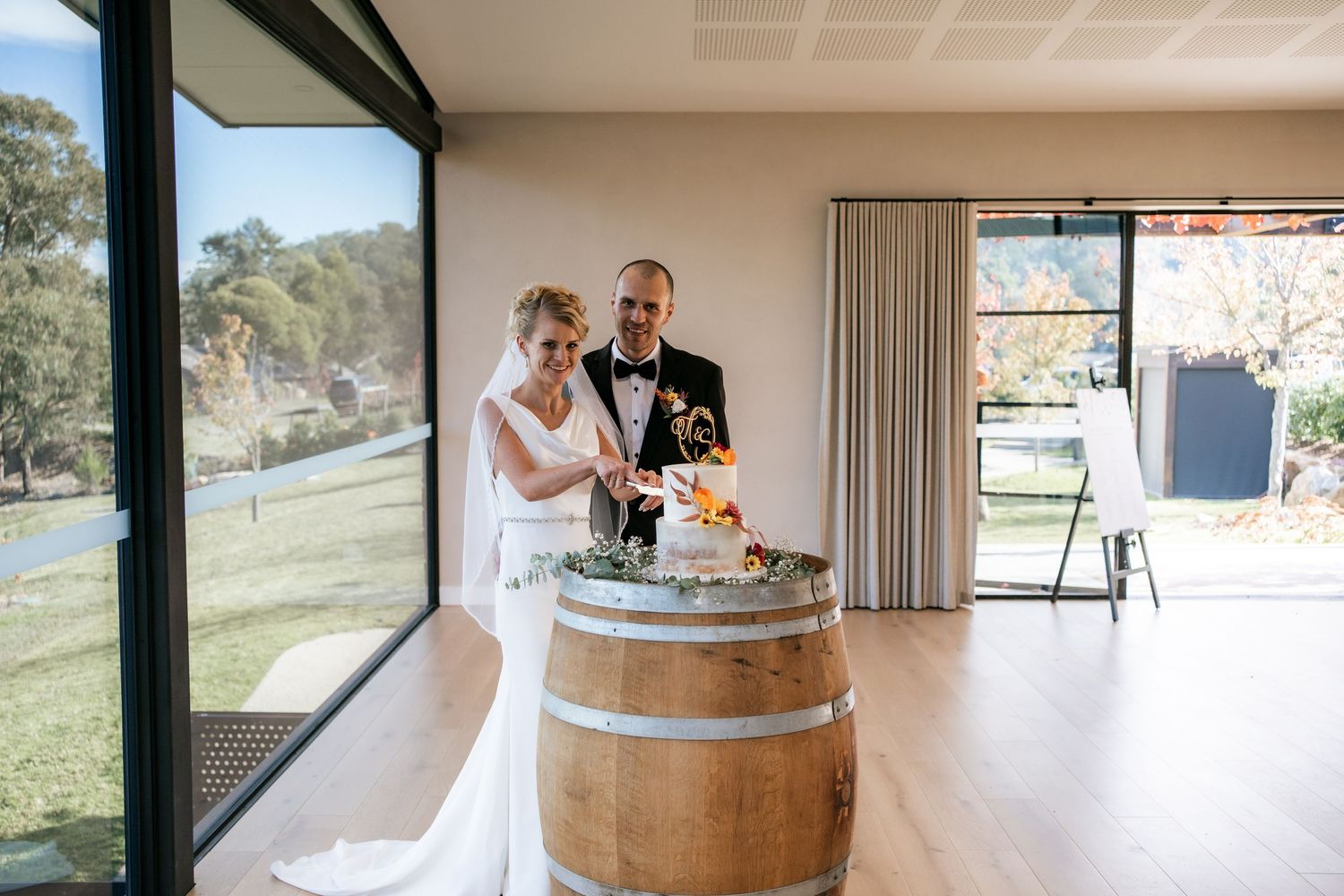 Modern winery interior with wooden barrels and wedding cake display.