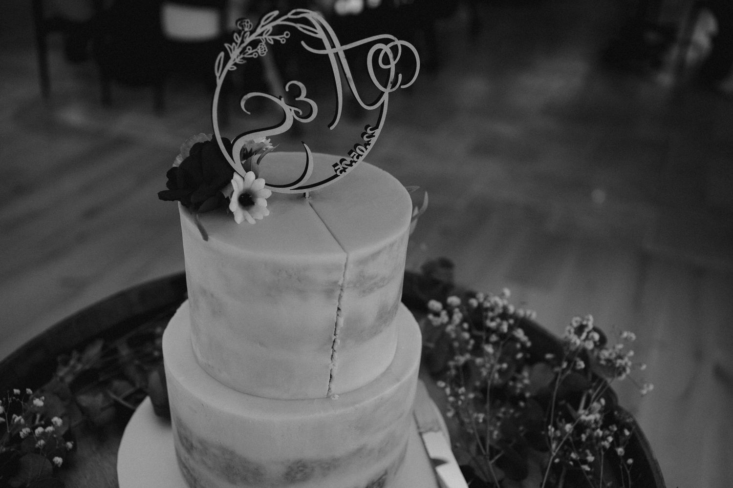 Black and white photo of wedding cake with whimsical wire bird topper decoration.
