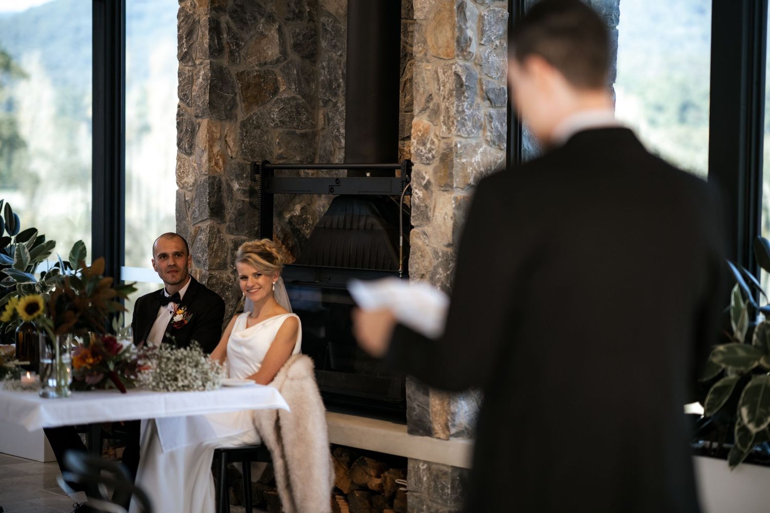 Interior of a rustic stone venue with large windows during a wedding reception.
