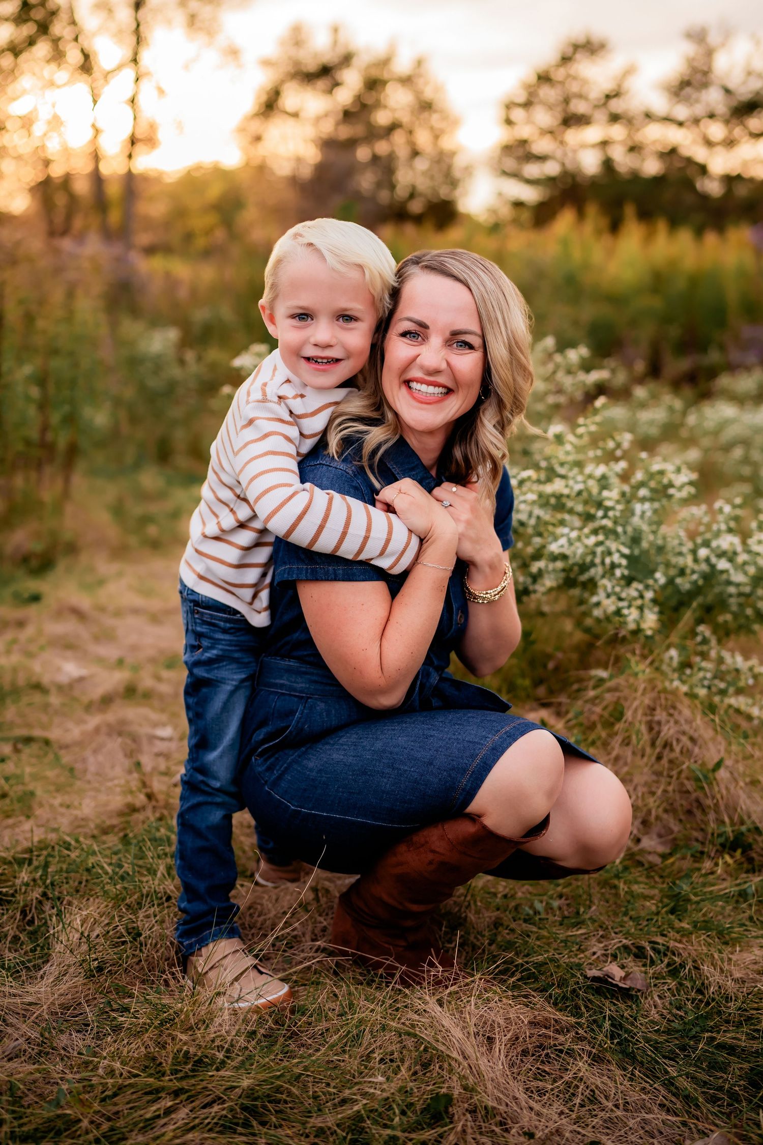 Tender moment between parent and child sitting in wildflower field at golden hour.