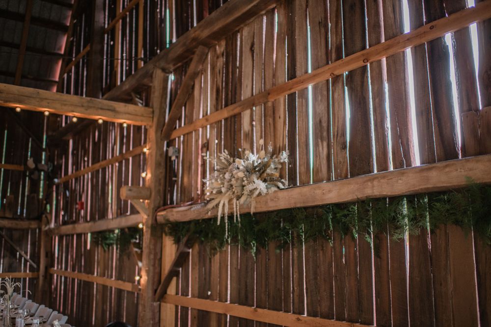 Rustic wooden barn interior with dried floral arrangement on exposed timber beams.