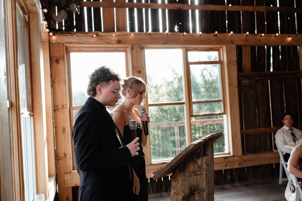 Couple stands together reading in rustic wooden barn with natural light streaming through window.