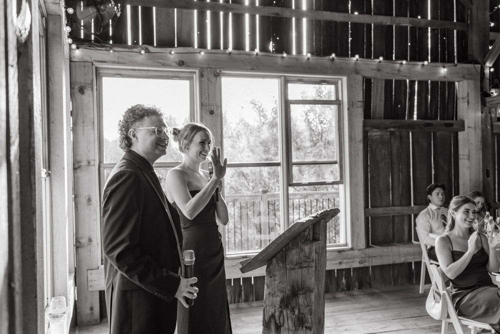 People gathered in a rustic interior space looking through a window in black and white photography.
