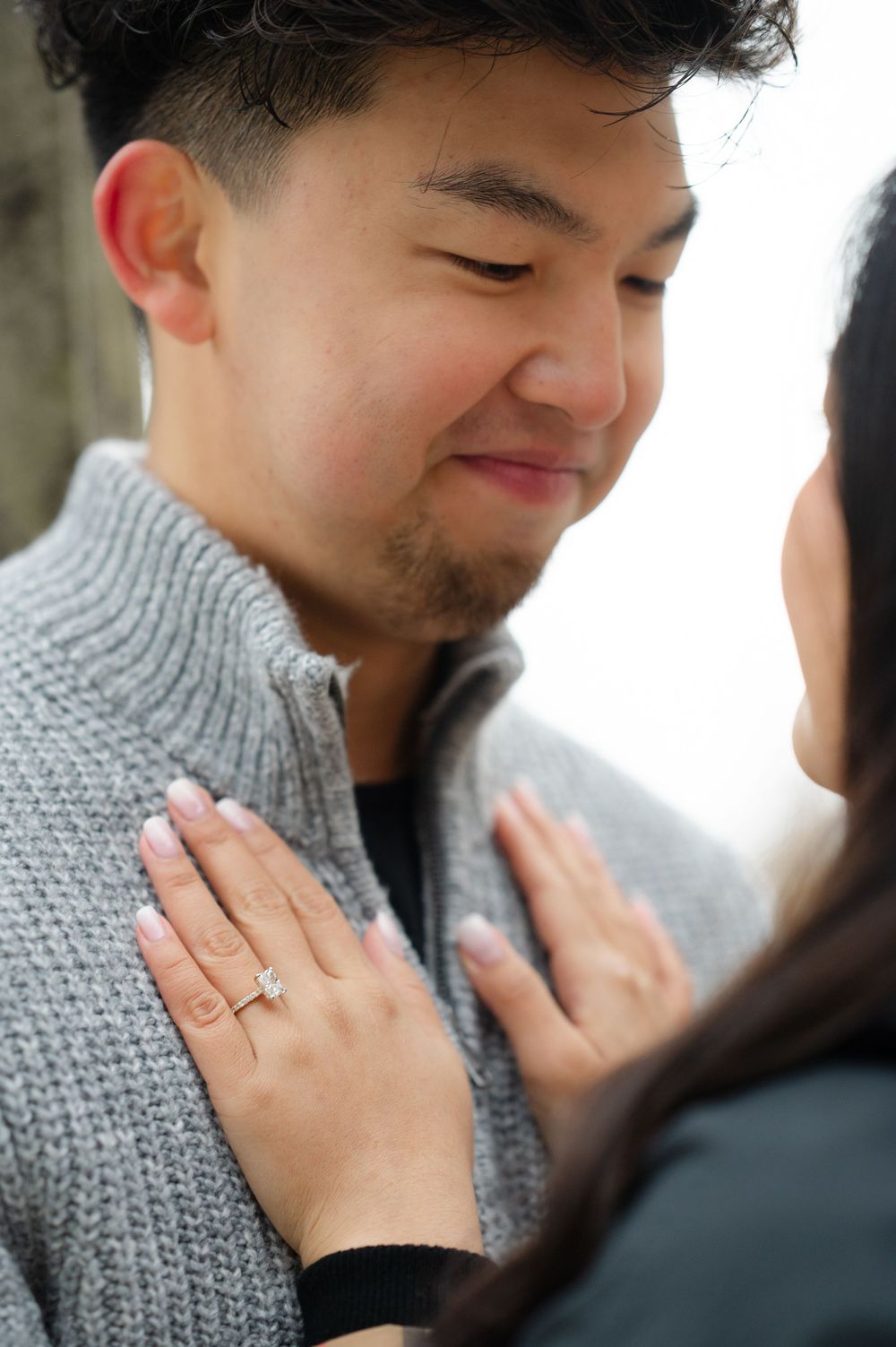 Close-up shot showing hands resting on a grey sweater with an engagement ring, photo by Joliette Marie Photography