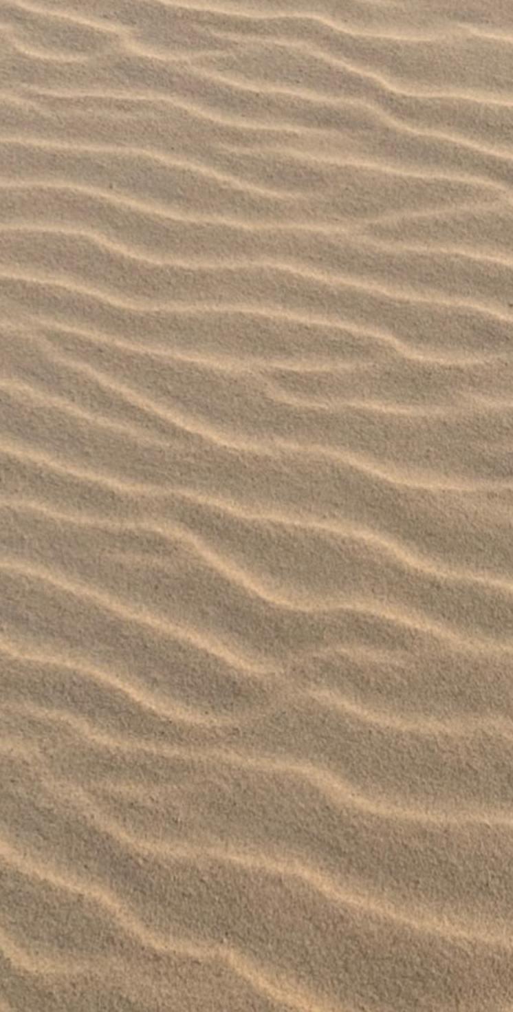 Close-up of rippled desert sand texture with wavy patterns created by wind erosion.