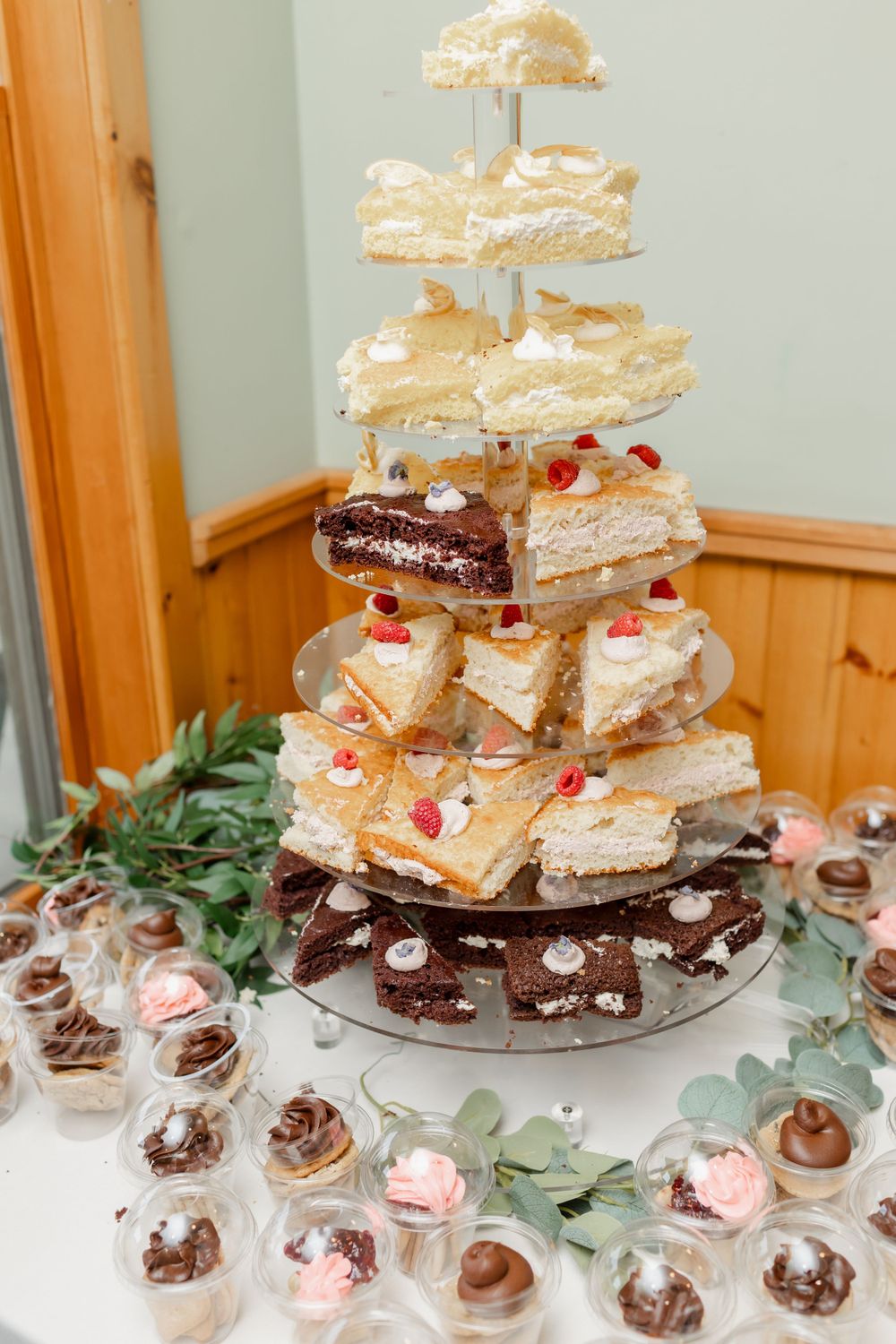 Multi-tiered dessert display featuring stacked pastries and chocolate treats on an elegant stand with greenery decoration.