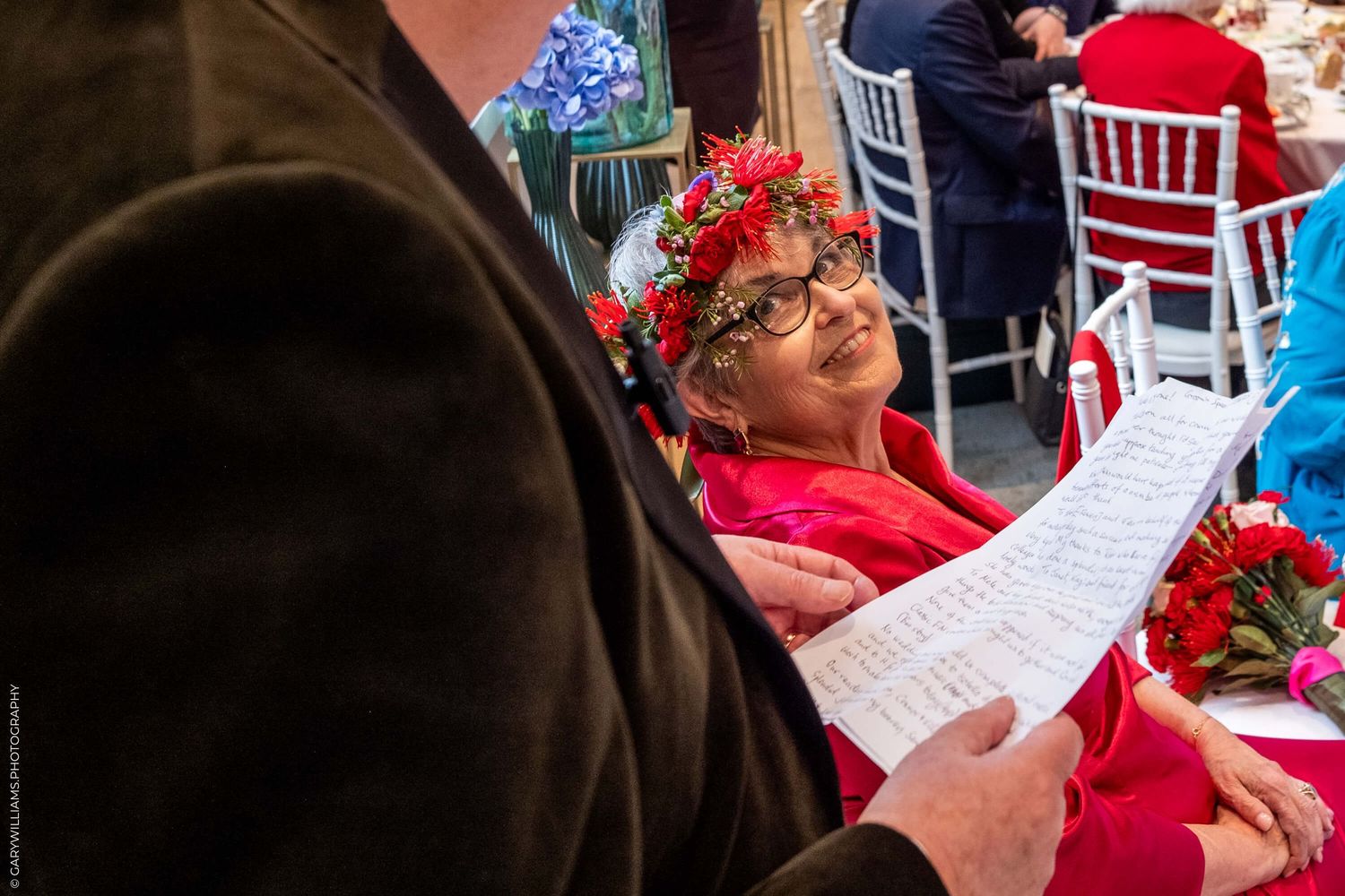 A reader wearing a festive red floral crown reviews sheet music at a holiday celebration.