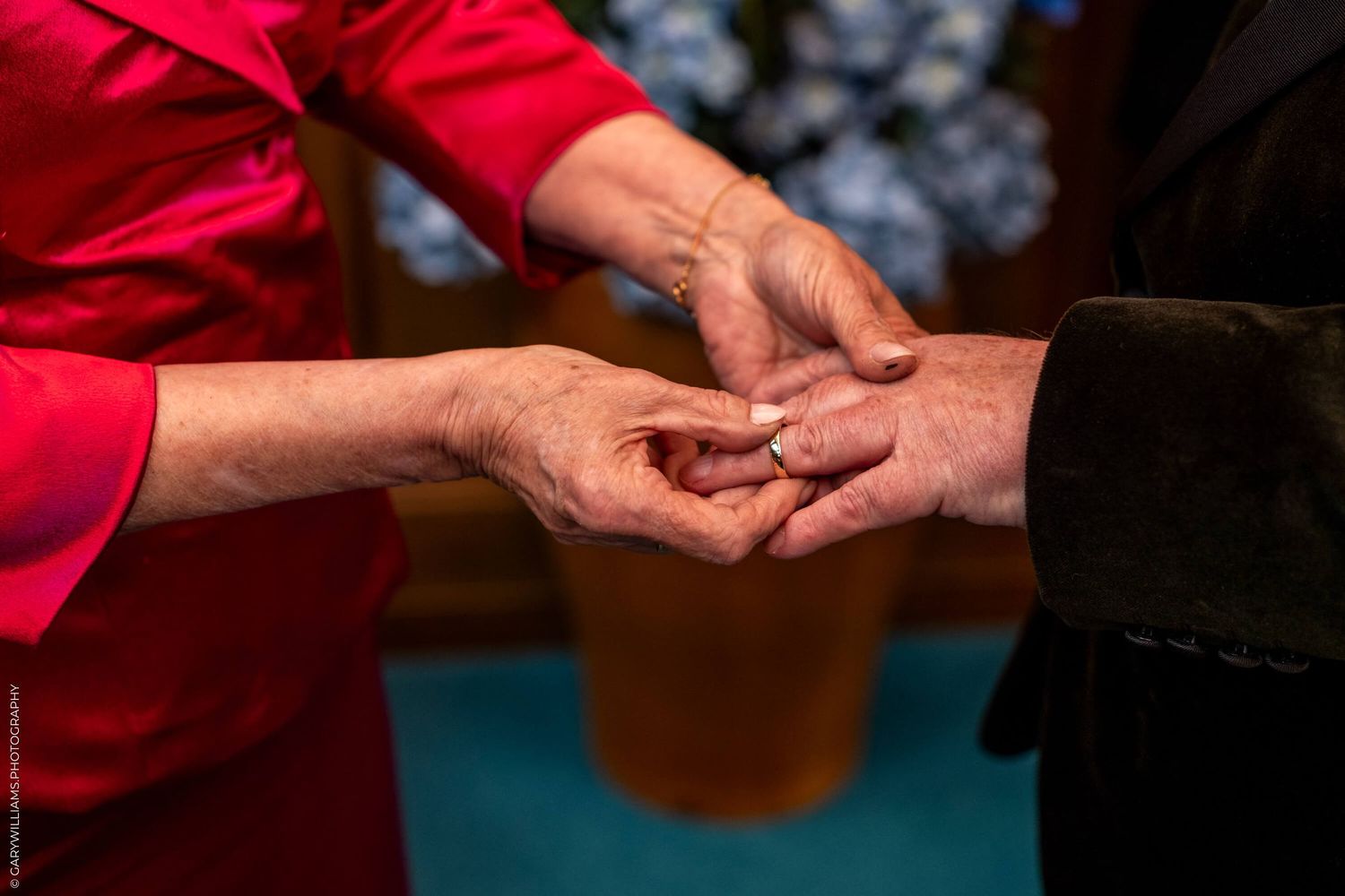 Close-up of hands exchanging what appears to be a ring in an intimate moment.