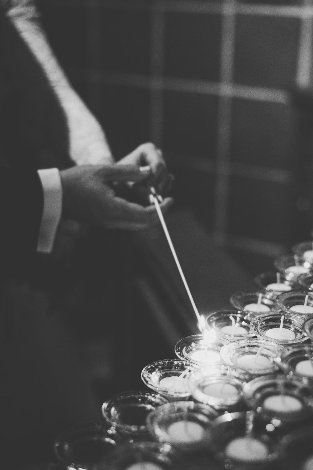Bride and groom together light a prayer candle in a catholic church on their wedding day.