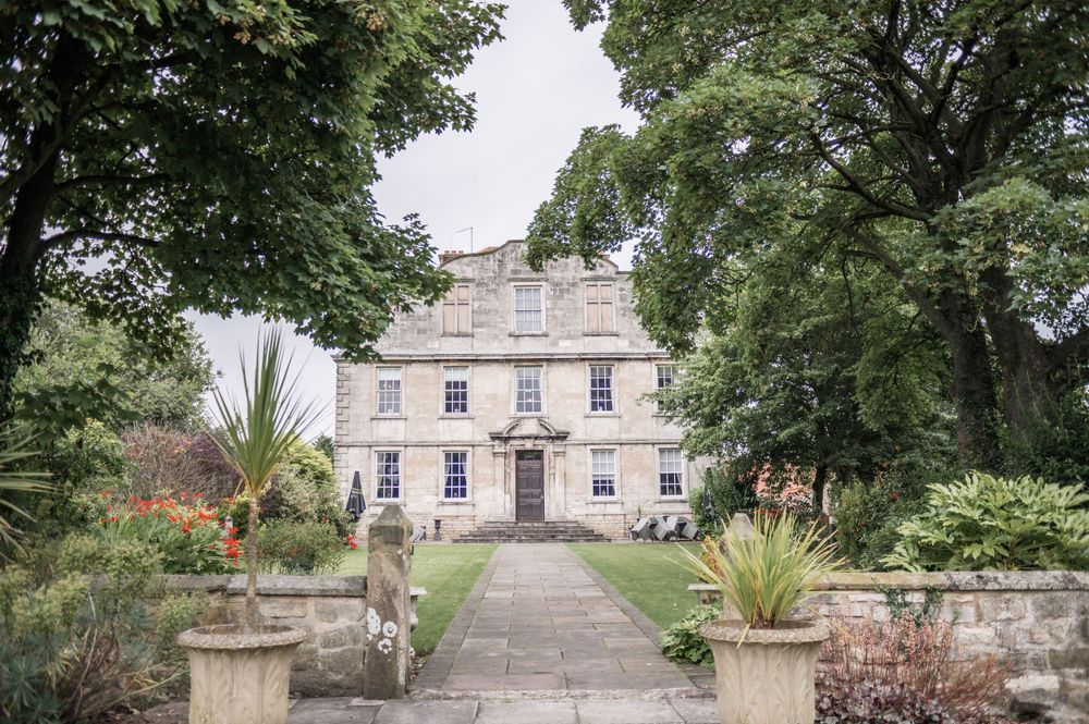 Historic stone manor house with manicured garden path and entrance.