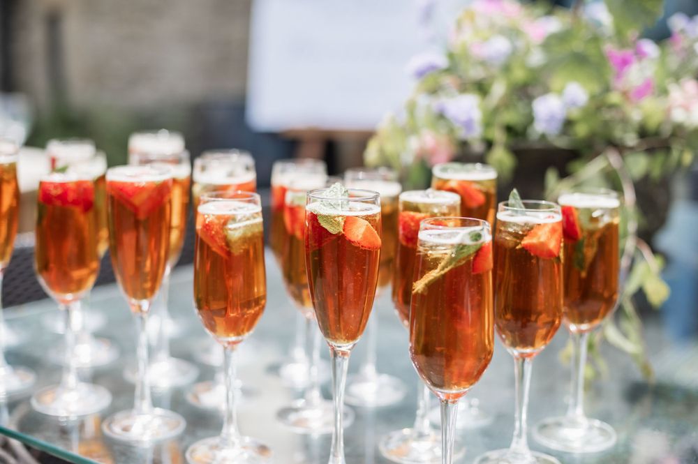 Rows of elegant champagne flutes filled with pink cocktails garnished with citrus slices.