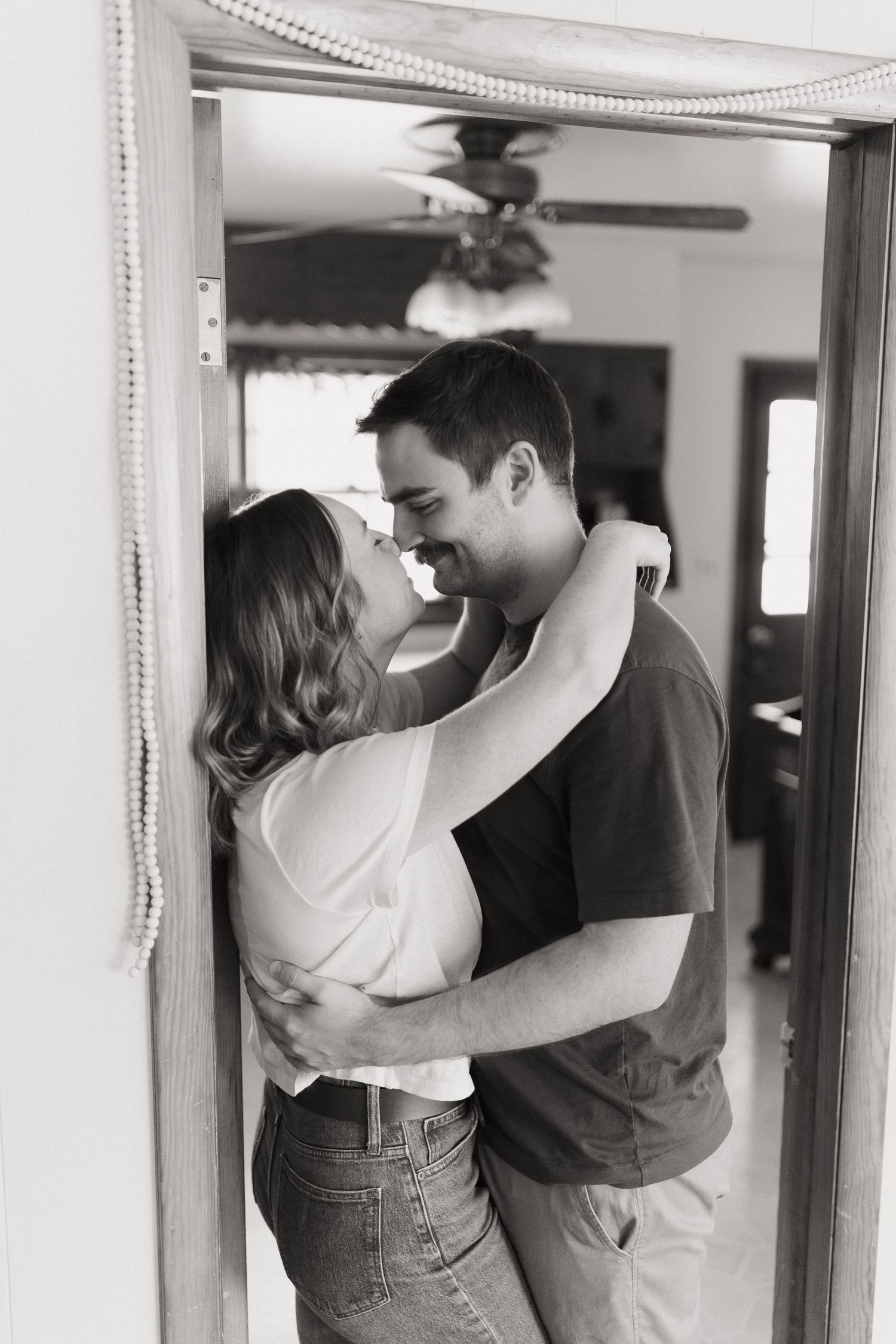 A black and white photo of an embrace in a doorway with romantic lighting.