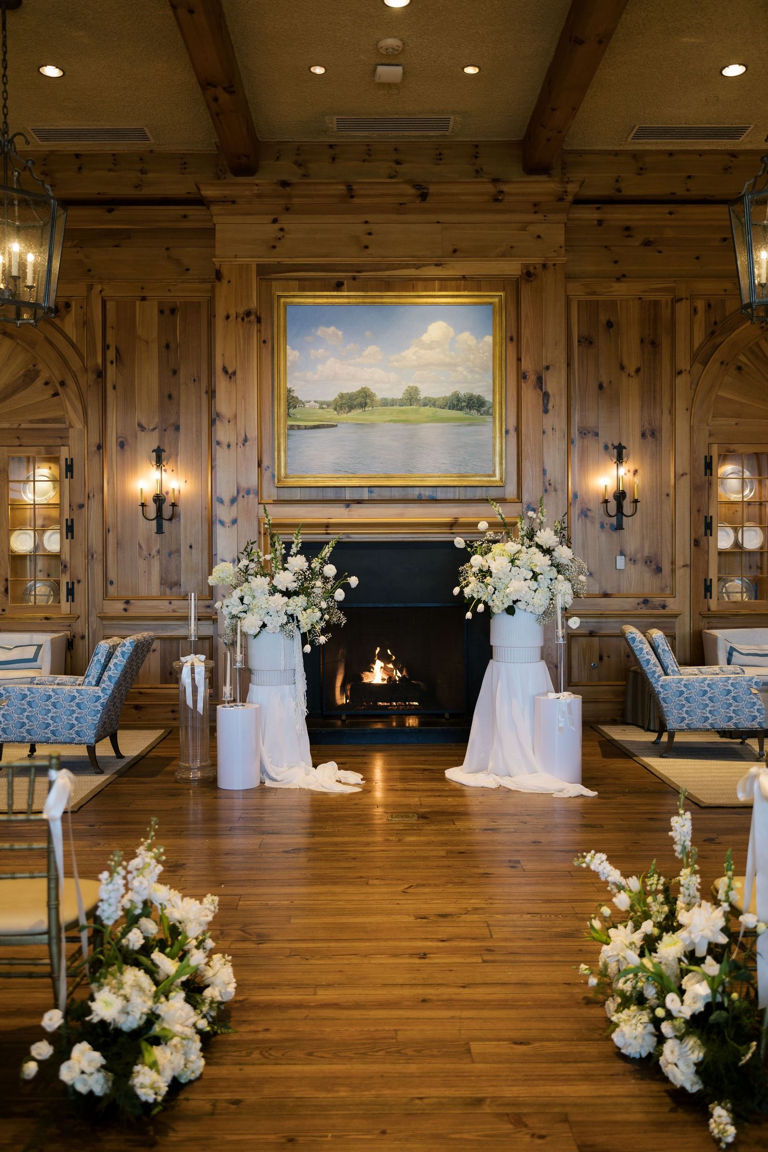 Wedding ceremony space with wooden walls, floral arrangements and landscape painting. NC WEDDING PHOTOGRAPHER, LUXURY WEDDING PHOTOGRAPHER