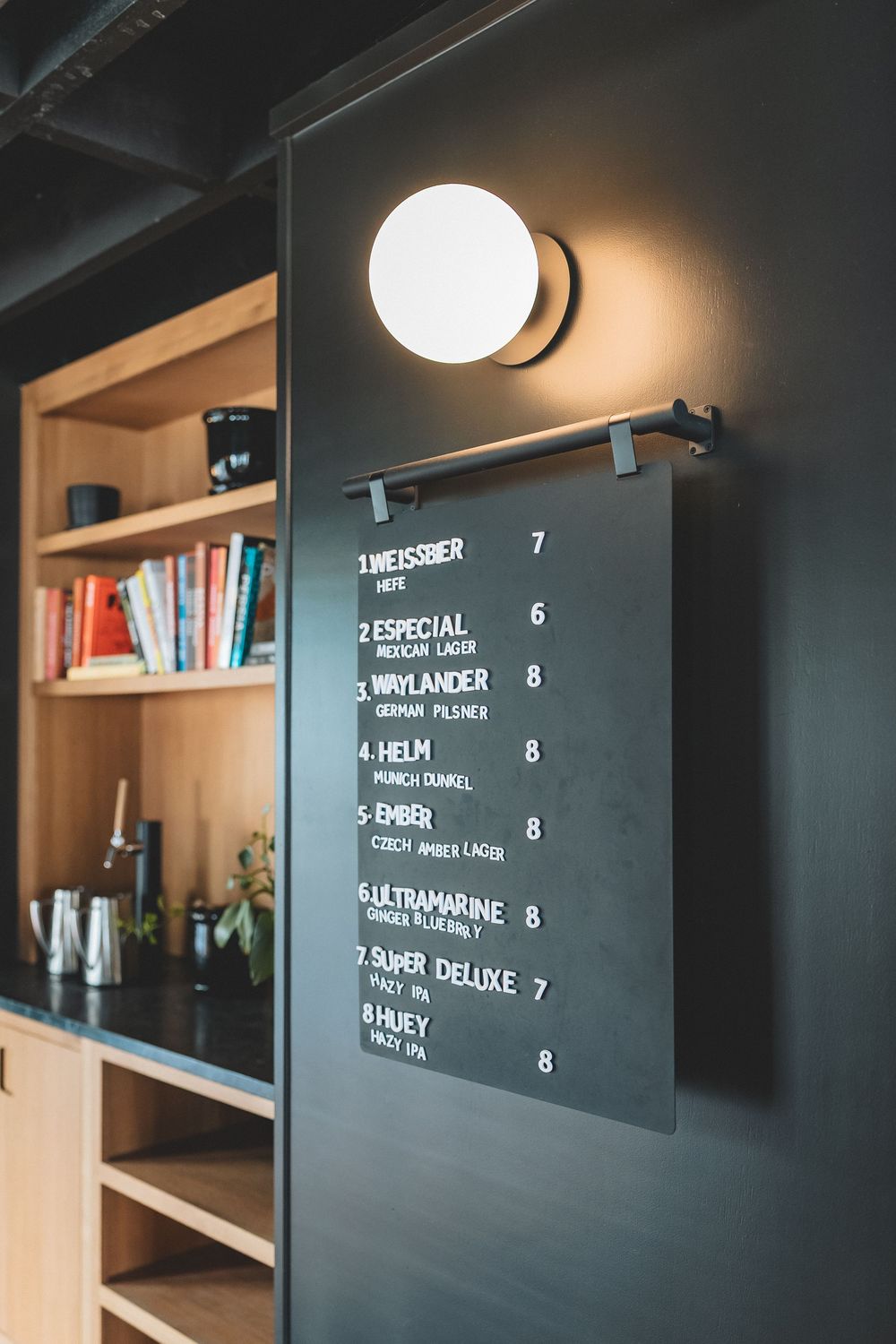 Black chalkboard menu with prices and items listed under modern circular wall lighting.