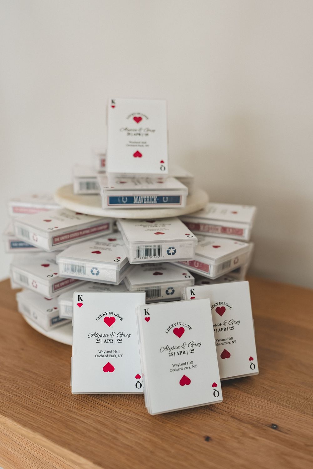 Stack of white playing card decks with red heart designs arranged on wooden surface.