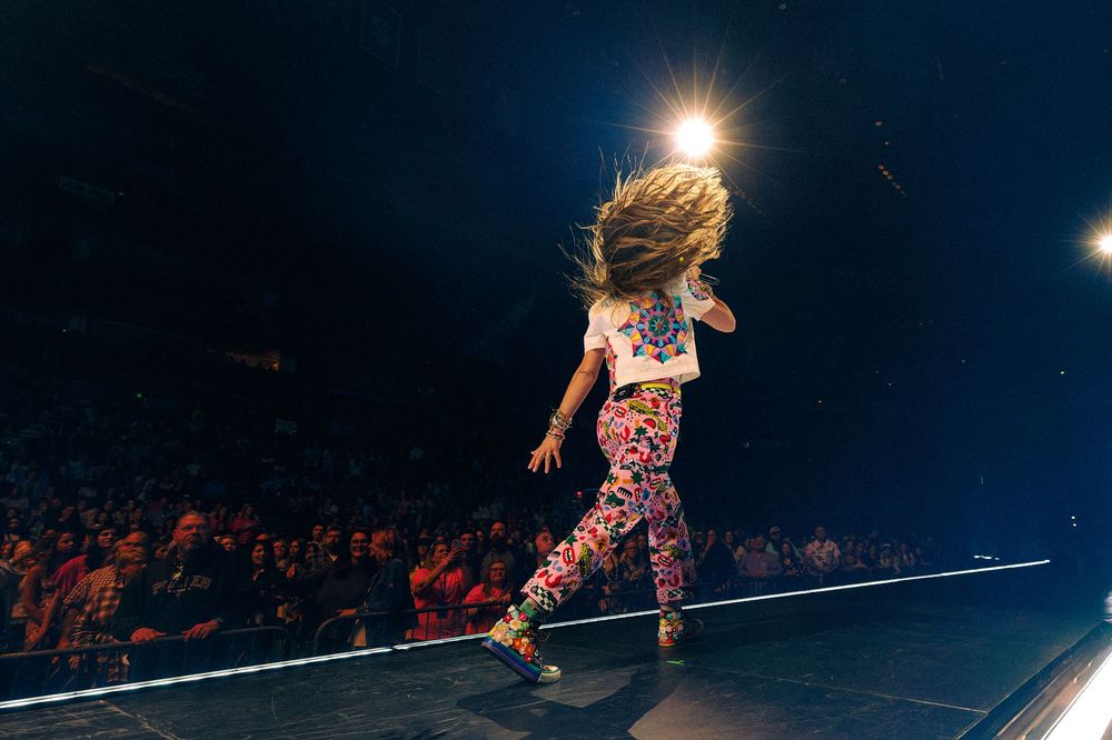 Christian artist Lauren Daigle walks dynamically across a concert stage with dramatic lighting and crowd in background at Bridgestone.
