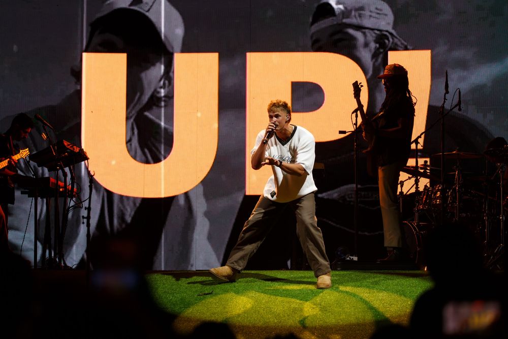 Christian hip-hop artist Forrest Frank stands energetically on stage with large orange letters visible in the background at Bridgestone.