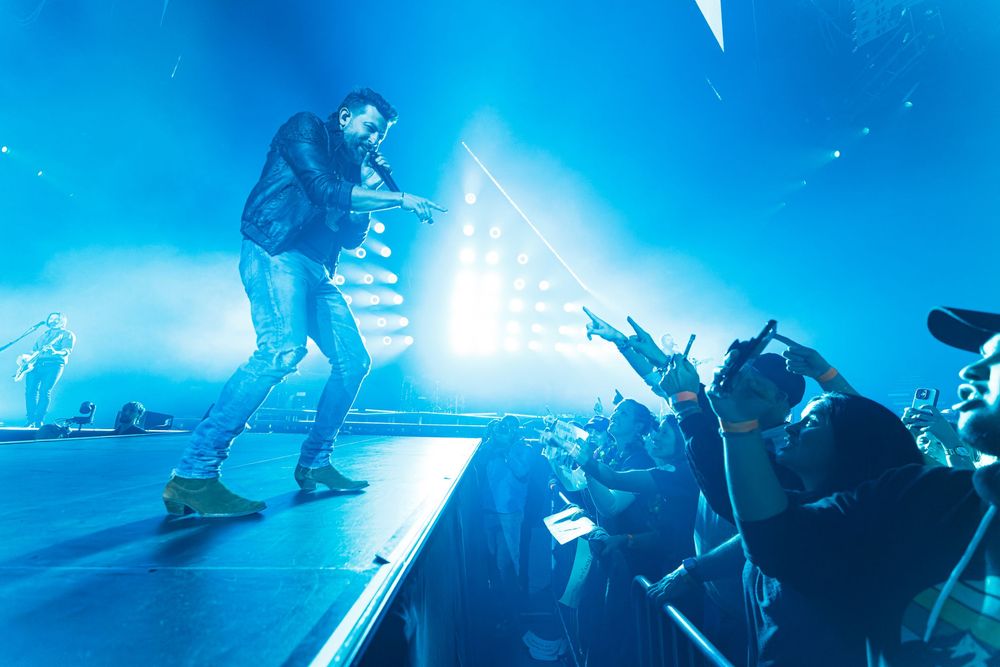 Matthew Ramsey of Old Dominion energetically engaging with crowd on stage under bright blue lighting effects at Bridgestone Arena.