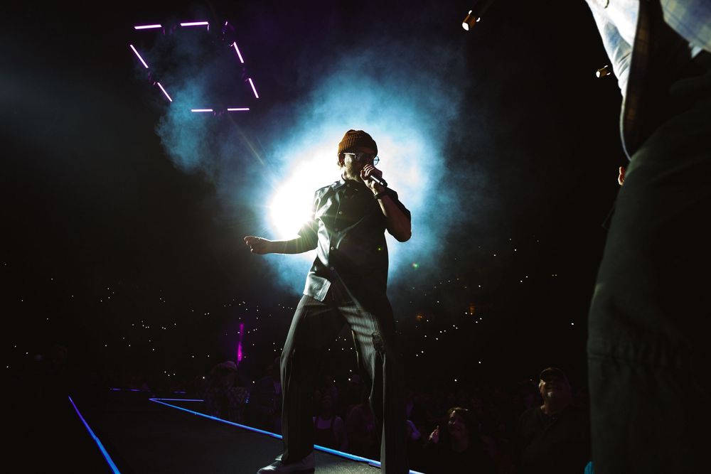 Silhouette of performer Toby Mac on stage surrounded by atmospheric smoke and dramatic lighting effects at Bridgestone Arena in Nashville.