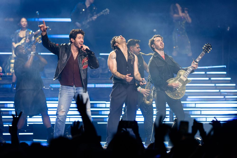 Pop musicians Jonas Brothers perform on a concert stage with dramatic lighting and an energetic atmosphere at Bridgestone Arena.