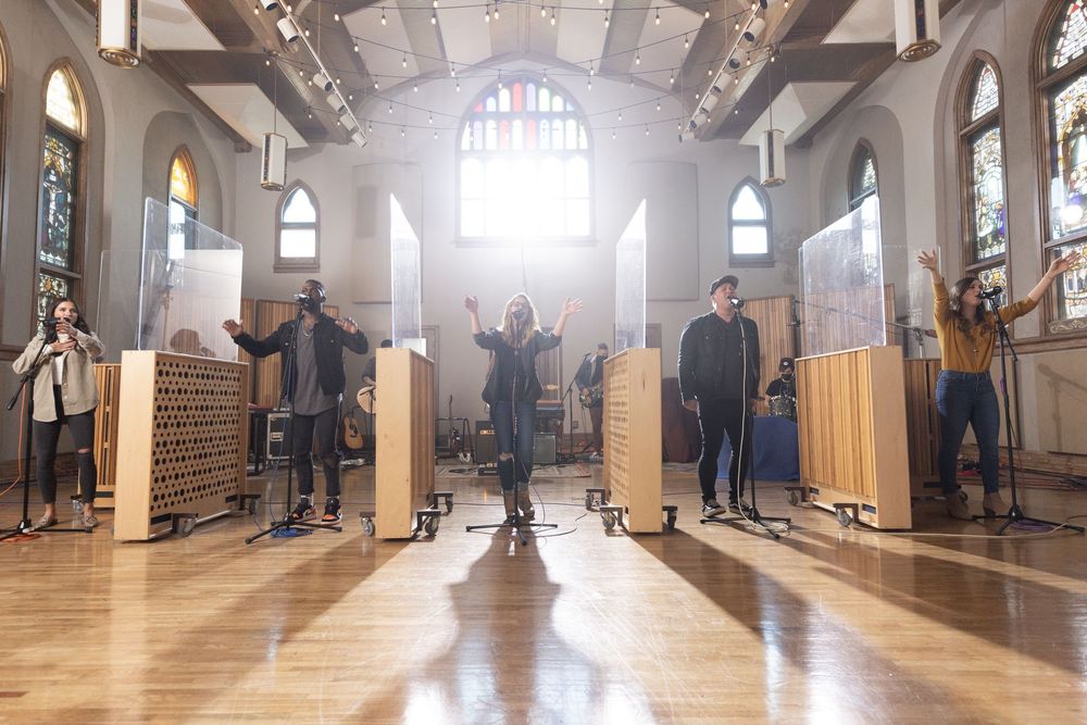 Musicians perform in sunlit church interior with wooden partitions and stained glass windows for Cross Point Music.