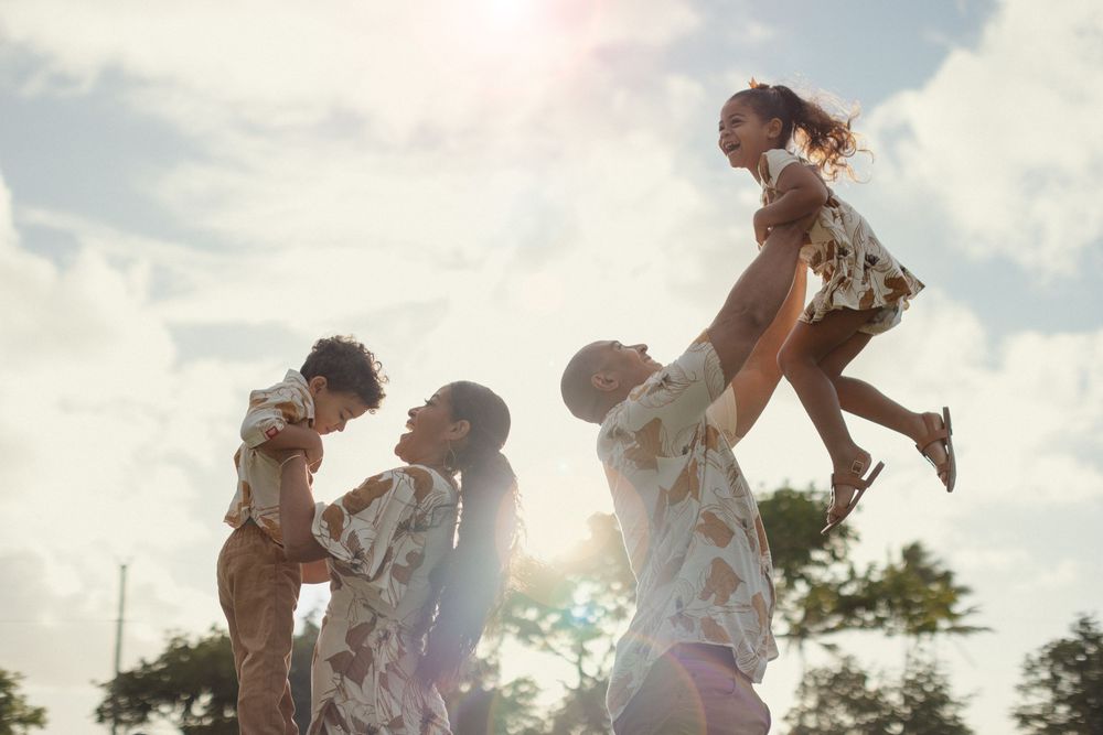 Family members playing together outdoors in sunlight during a carefree summer afternoon.