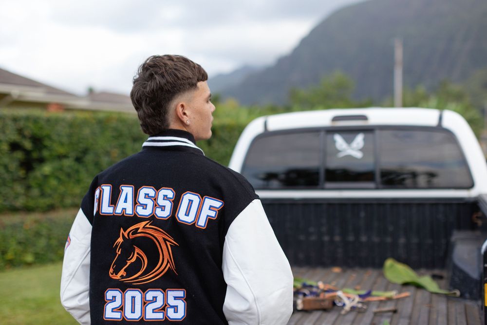 A letterman jacket with 'Class of 2025' and a bronco mascot logo displayed outdoors with mountains in the background.