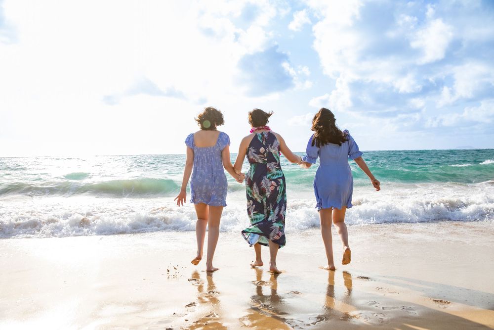 Three friends walking together in the ocean surf on a sunny beach day.
