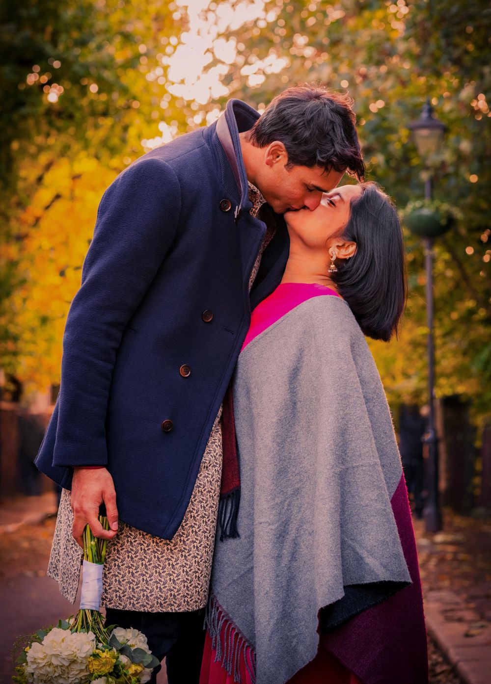 Couple sharing intimate moment in autumn park with golden foliage background.