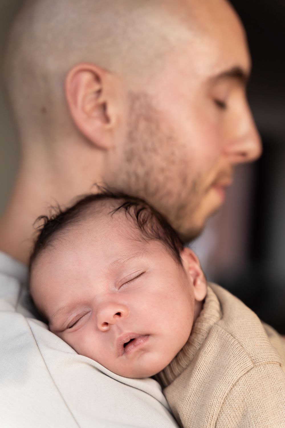 newbornshoot van een pasgeboren baby, hij rust op vaders schouder. vastgelegd in warme tinten. in een huiselijke sfeer in beneden-leeuwen