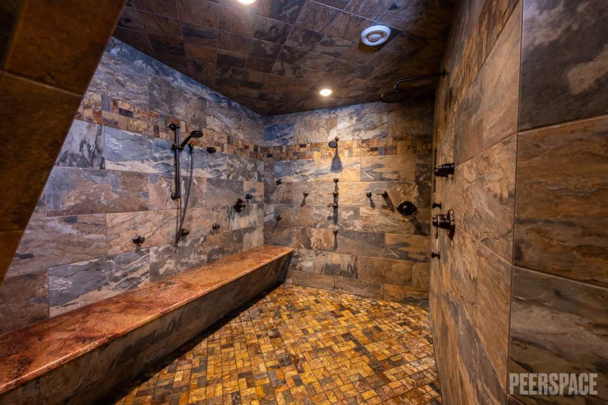Stone-walled steam room with wooden bench seating and mosaic tile flooring creates a spa-like atmosphere.