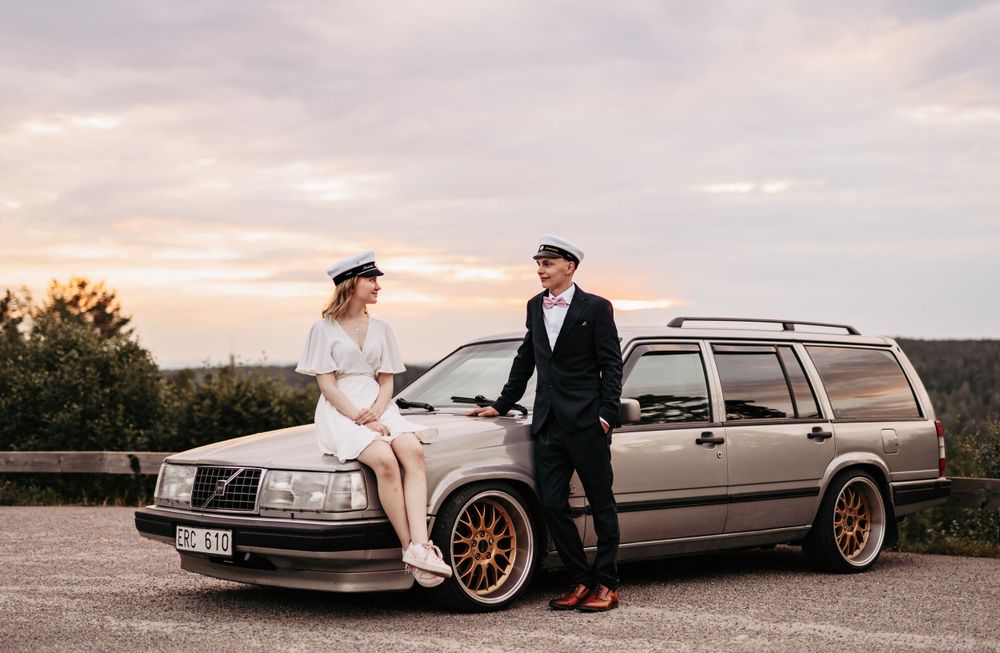 A classic Volvo station wagon features in a romantic sunset photoshoot with a vintage-inspired fashion aesthetic.
