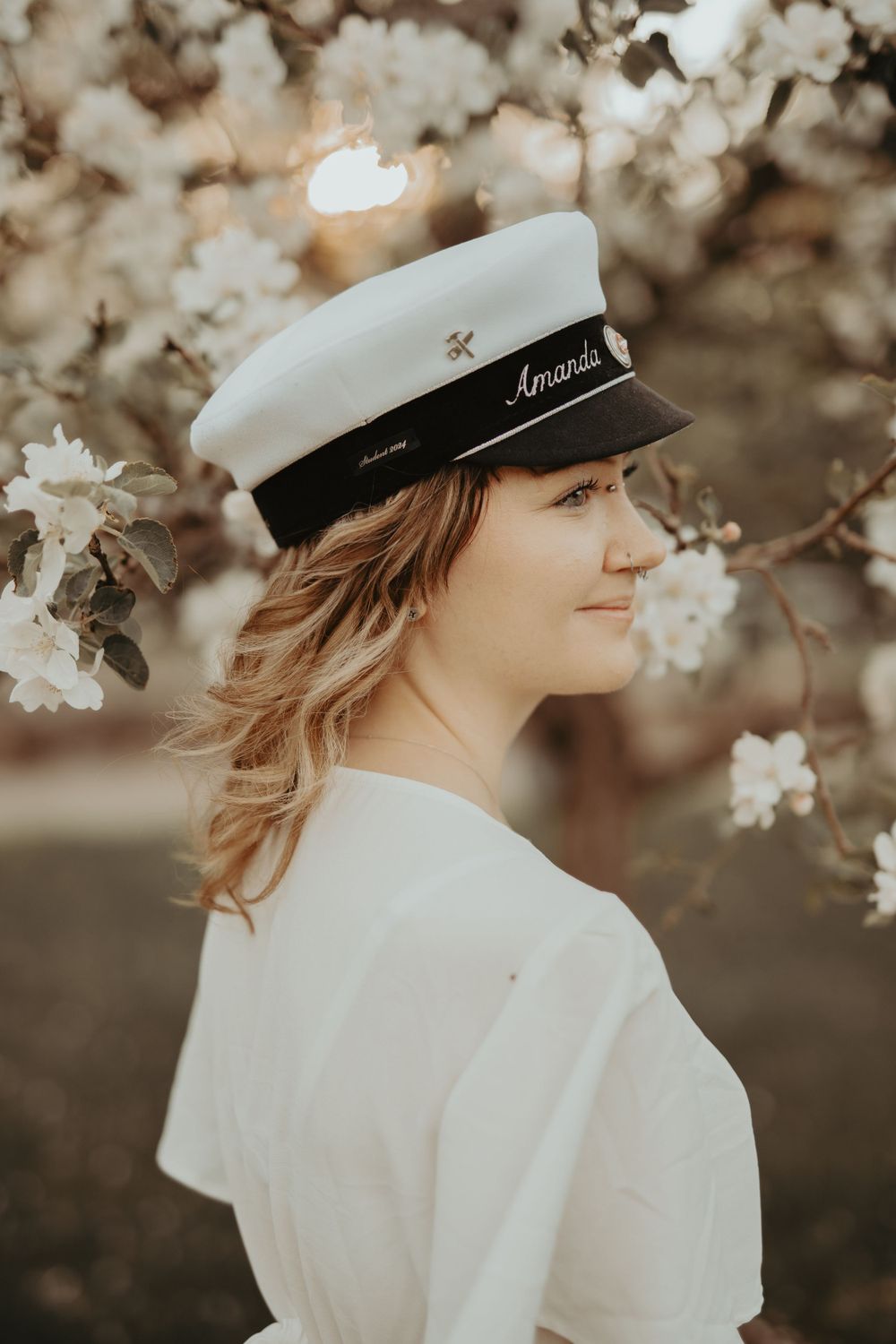 Vintage-inspired portrait with sailor cap surrounded by delicate cherry blossoms.