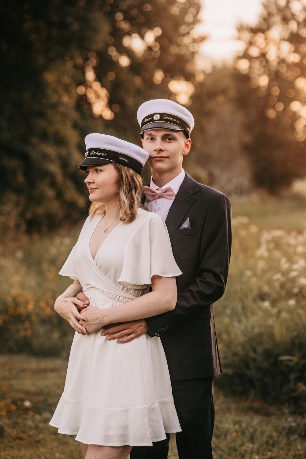 A romantic portrait session in white attire and traditional caps during sunset.