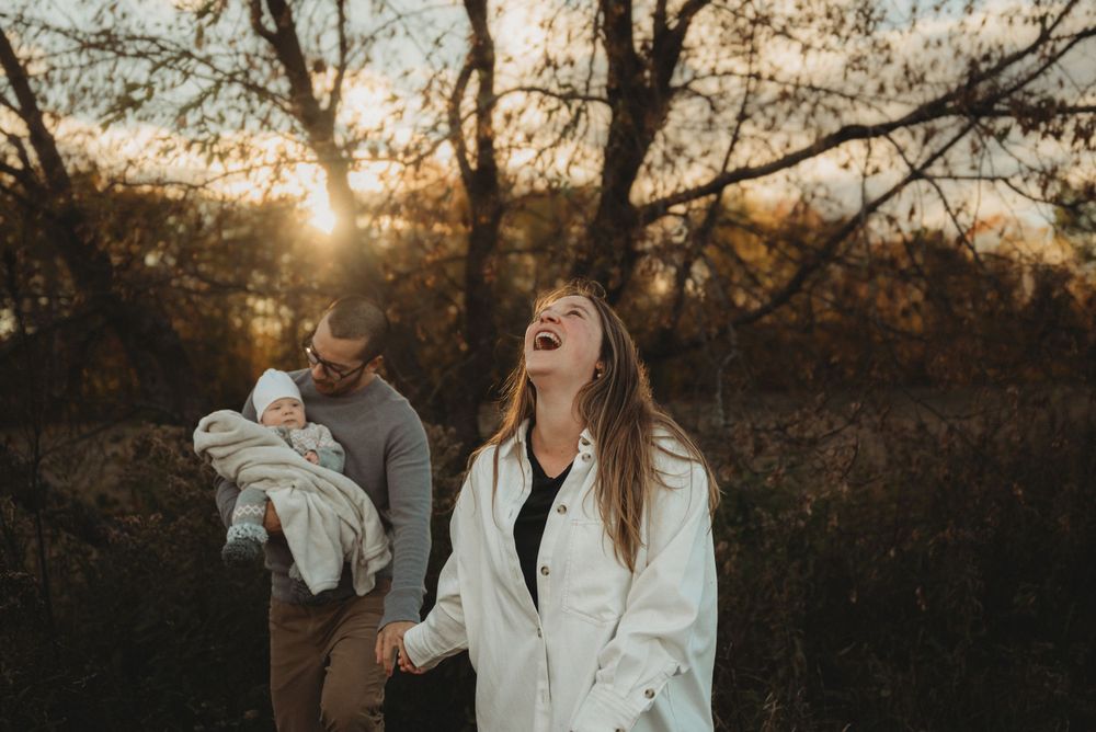 Candid laughter during sunset family photoshoot in autumn woods.