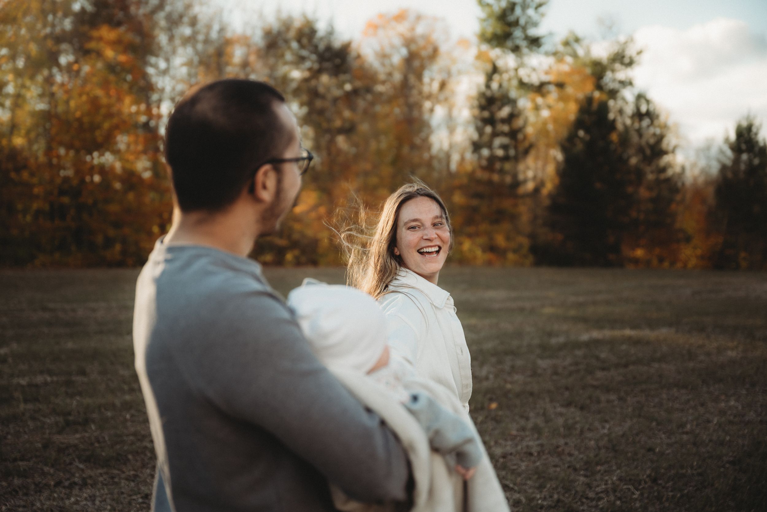 A candid family moment filled with laughter in an autumn field at sunset.