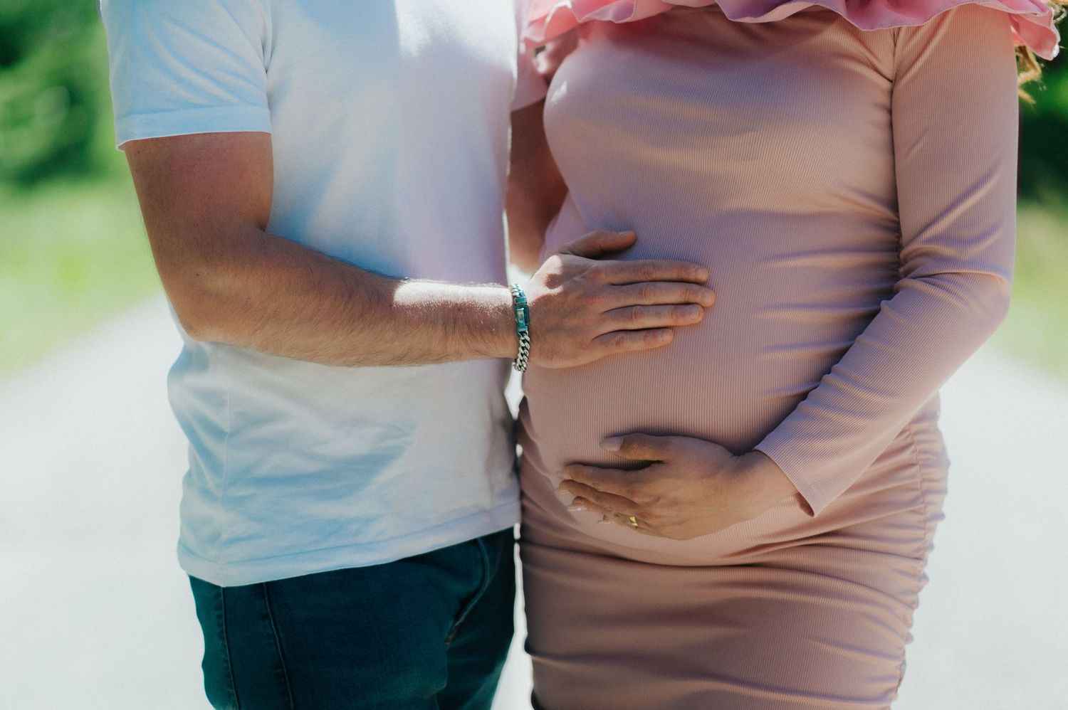 Close-up shot of hands tenderly cradling a pregnant belly.
